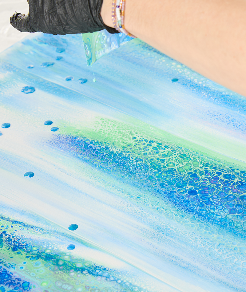 Mit Hilfe einer Folie wird die Farbe über die Leinwand gezogen